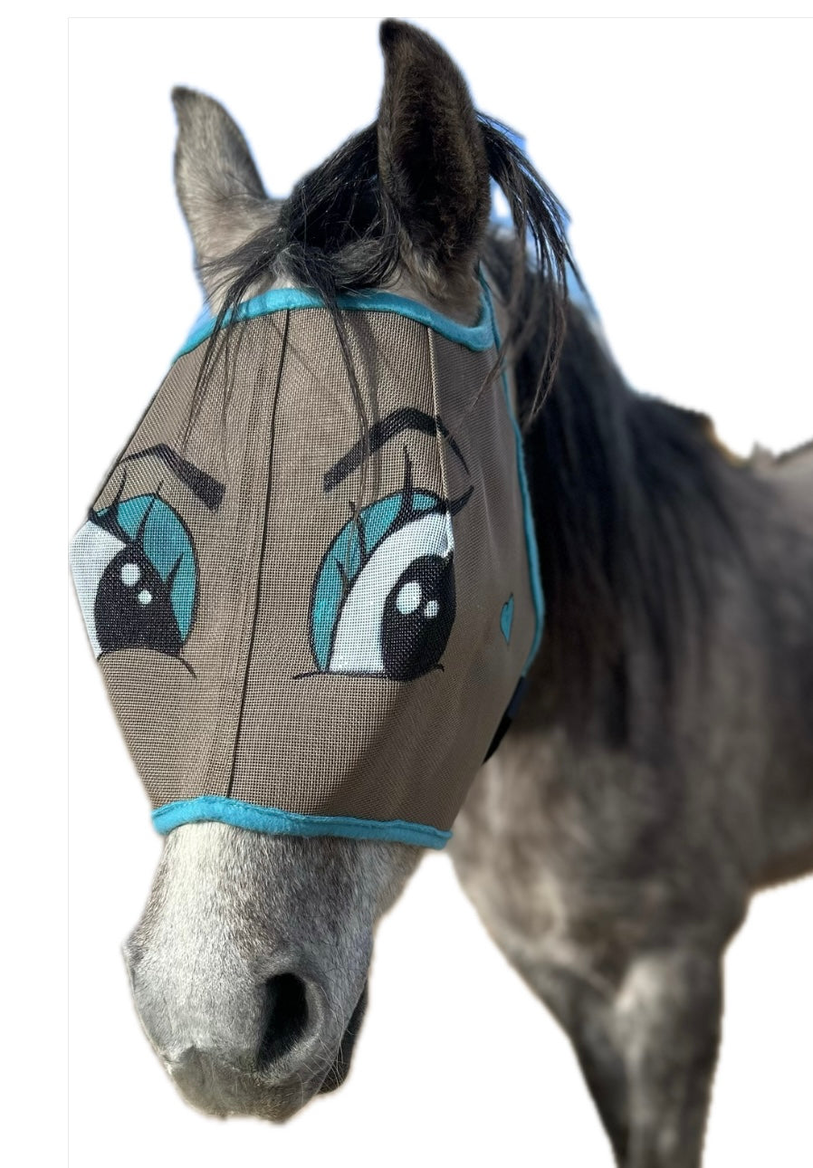 Grey horse with a fly mask. The mask is taupe with teal trim. Flirty cartoon eyes are hand painted on the mask complete with blue eyeshadow.