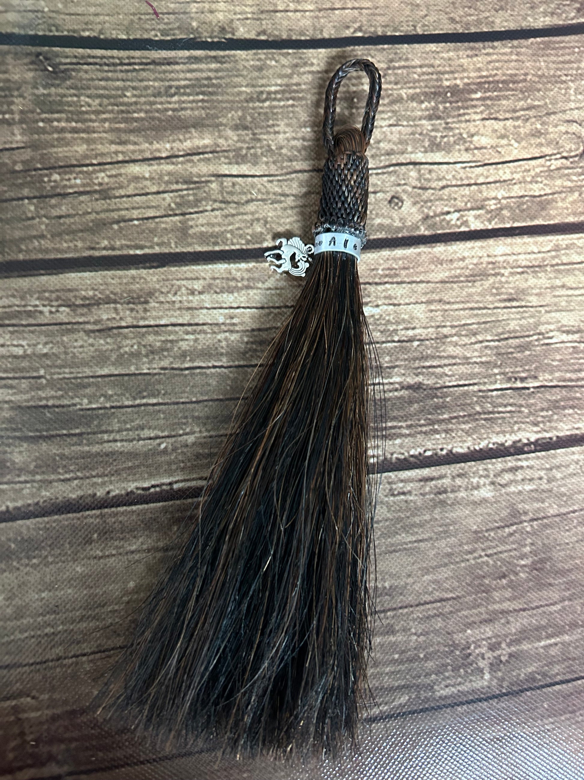 Tassel made of horse hair with a metal band including the horses name and a small horse charm