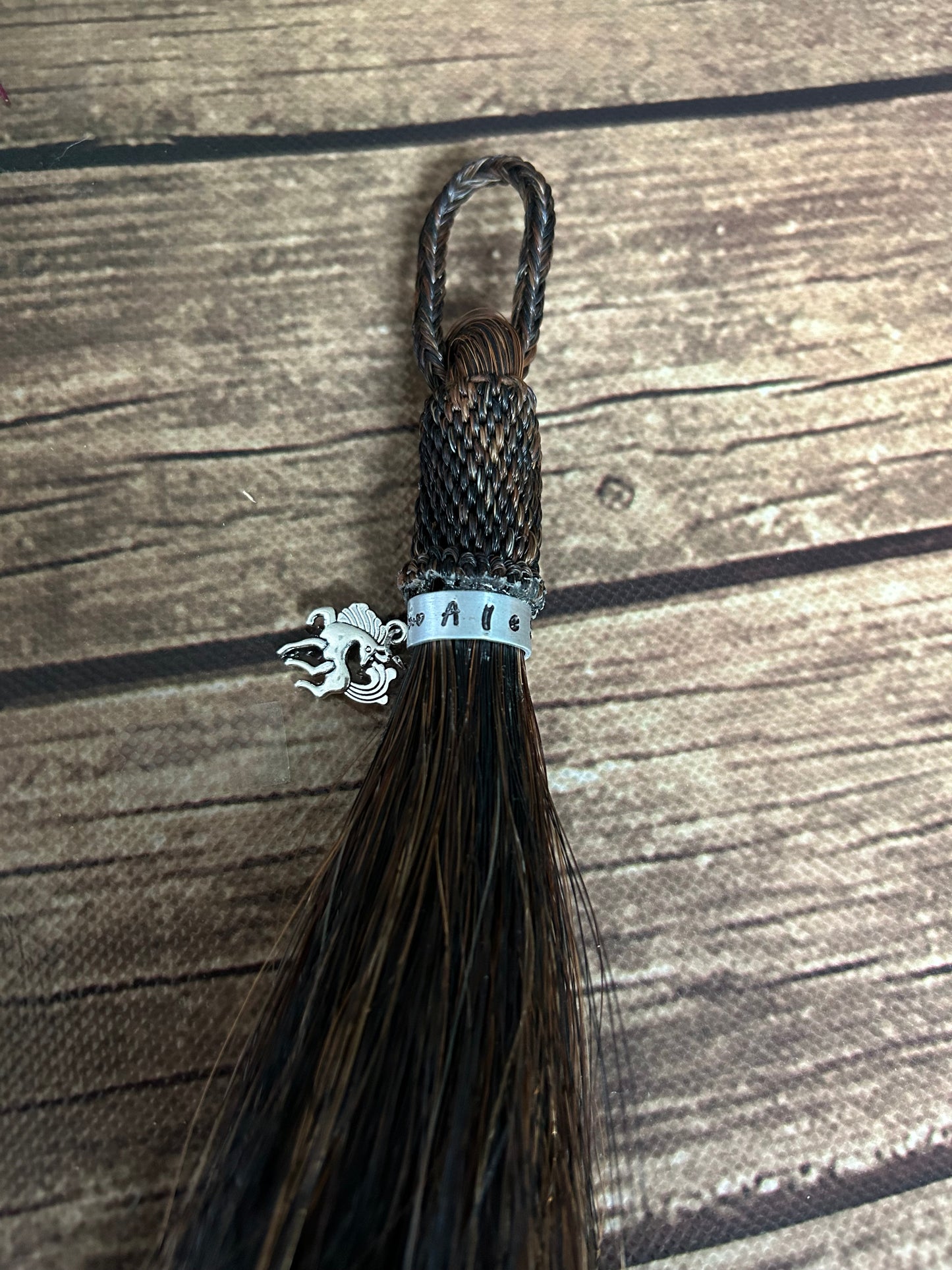 Close up - Tassel made of horse hair with a metal band including the horses name and a small horse charm